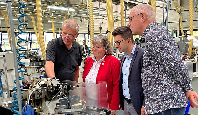 Vier Menschen stehen interessiert vor einer Maschine