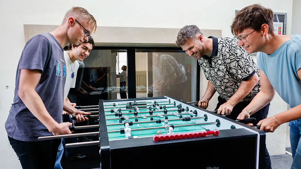 Unsere Abgeordneten Benjamin Bauer und Lea Geldner spielen mit zwei Jugendlichen Tischkicker.