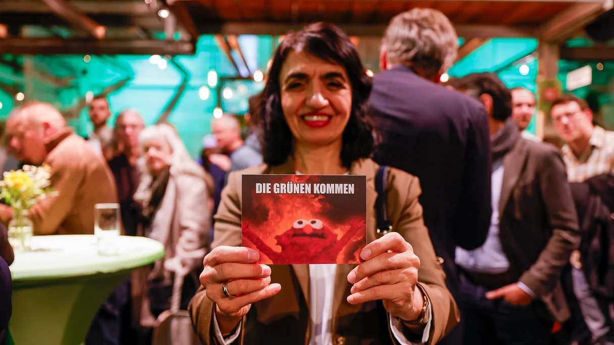 Muhterem Aras hält eine Karte in die Kamera mit dem Slogan "Die Grünen kommen"