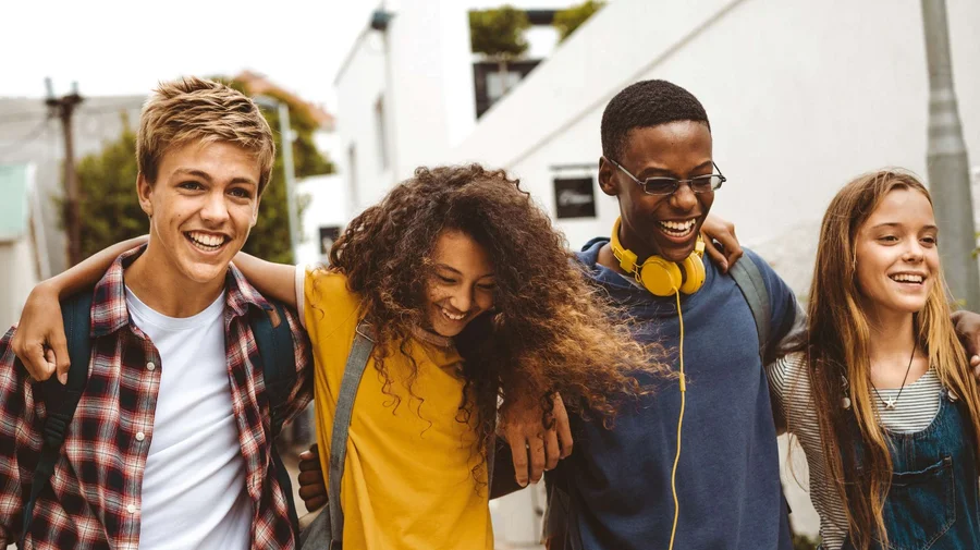 Vier junge Menschen gehen Arm in Arm und haben gute Laune.