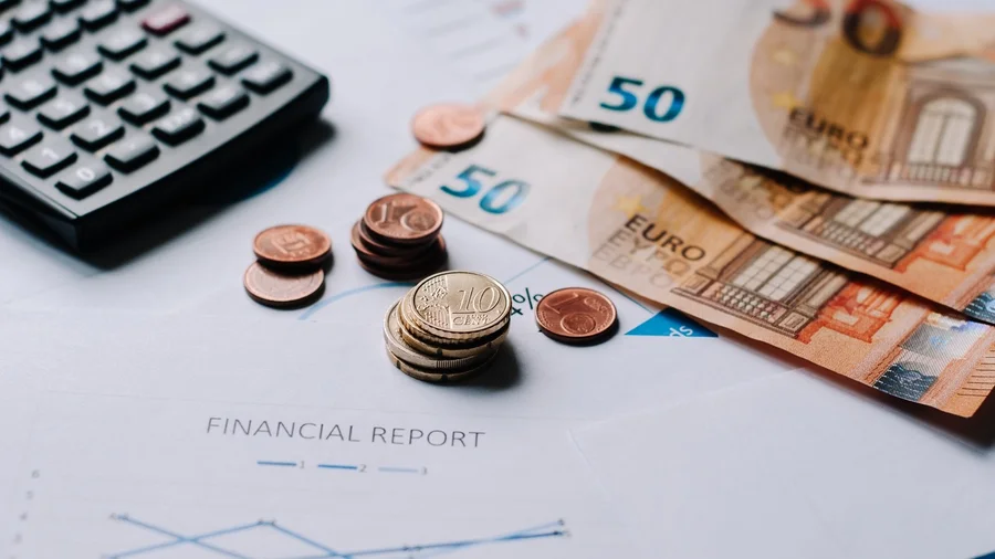 Auf einem Tisch liegen Taschenrechner, Münzen und Geldscheine.