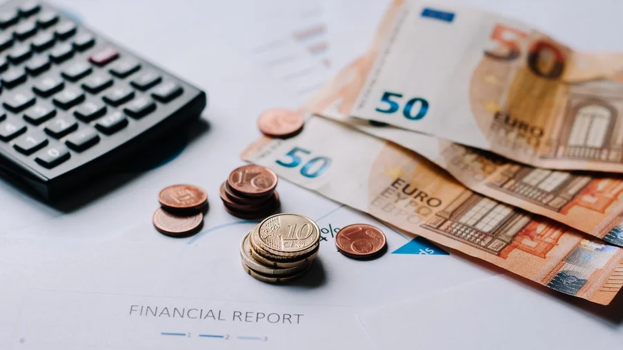 Auf einem Tisch liegen Taschenrechner, Münzen und Geldscheine.
