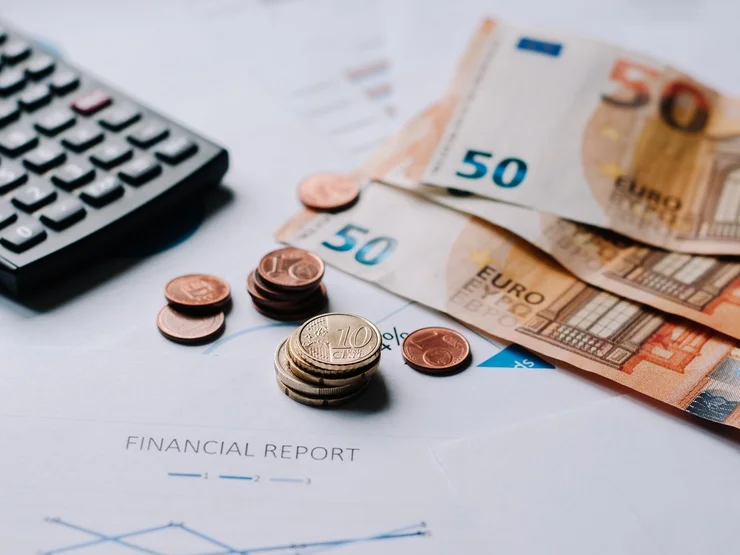 Auf einem Tisch liegen Taschenrechner, Münzen und Geldscheine.