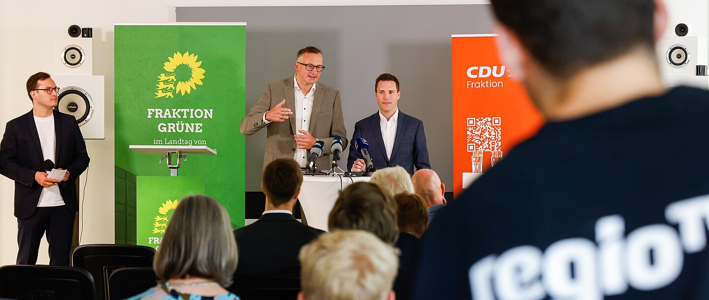 Andreas Schwarz und Manuel Hagel vor Journalist*innen während der Halbzeit-Pressekonferenz 2023.