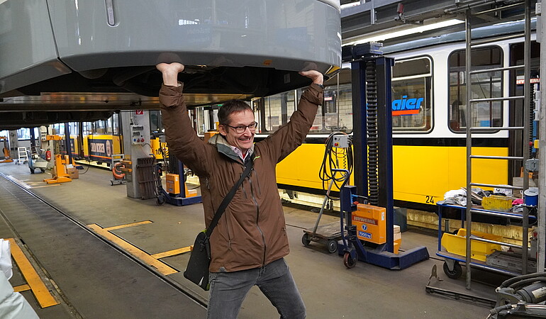 Um besser an die Unterbodentechnik des Siemens Avenio-Fahrzeugs zu gelangen, hebt MdL Hermino Katzenstein die Straßenbahn einfach an