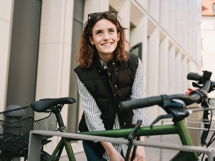 Junge Person schließt ein grünes Fahrrad in der Stadt ab.