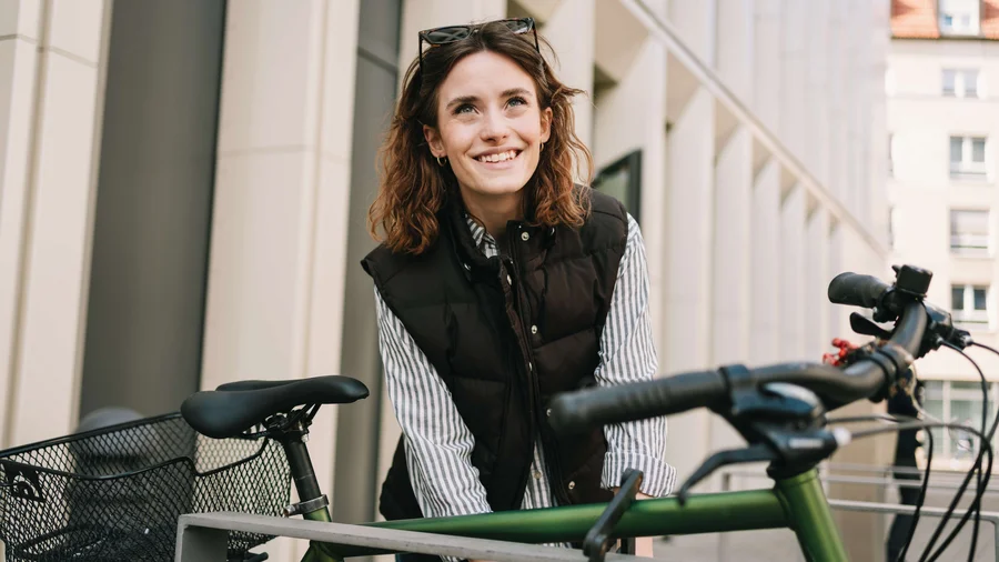 Junge Person schließt ein grünes Fahrrad in der Stadt ab.