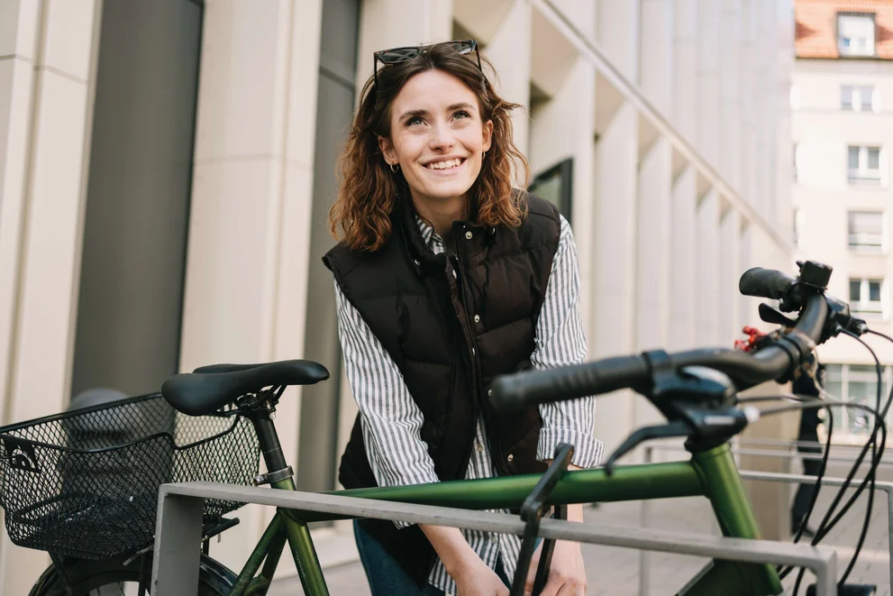Junge Person schließt ein grünes Fahrrad in der Stadt ab.