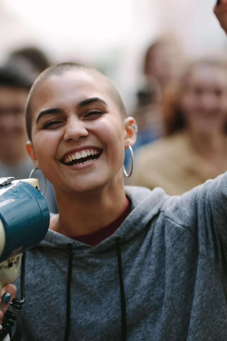Junger Mensch demonstriert mit einem Megaphone in der Hand.
