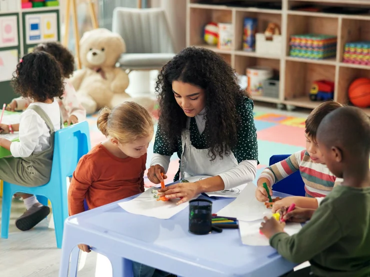 Kinder und Erzieherin malen gemeinsam in einer fröhlichen, bunten Kita-Umgebung.