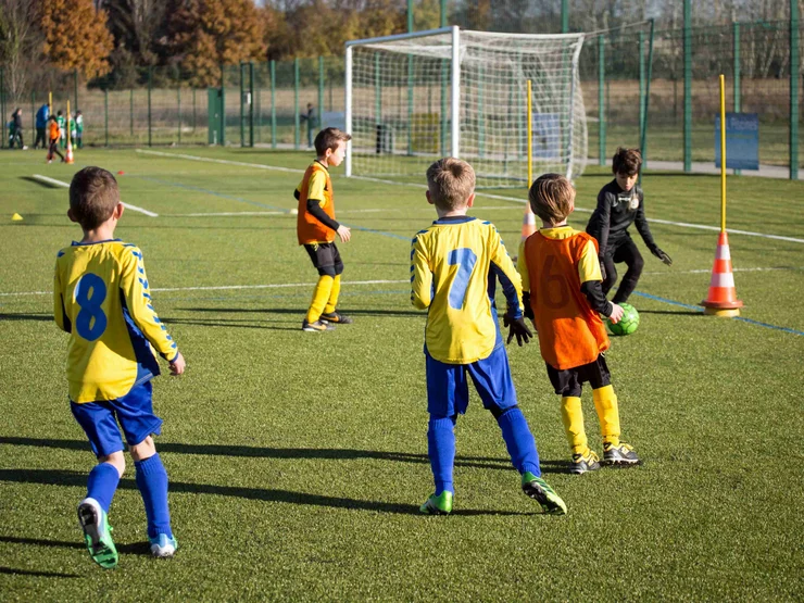 Kinder spielen draußen auf dem Feld Fußball.
