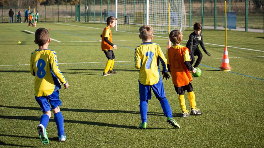Kinder spielen draußen auf dem Feld Fußball.
