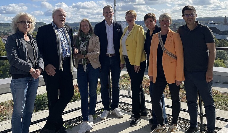 Mehrere Menschen stehen auf dem Dach des Holzhybridhochhauses 