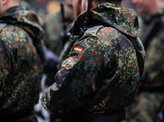 Menschen stehen bekleidet in der Bundeswehr-Uniform nebeneinander. 