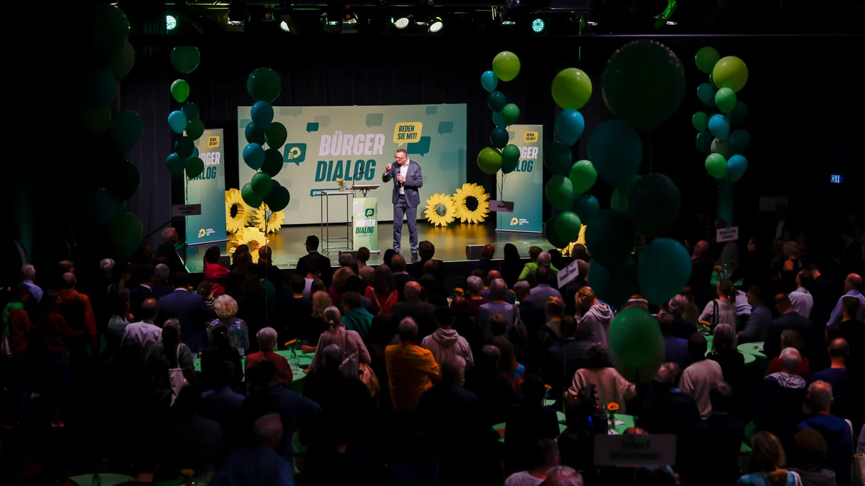 In einem Saal stehen über 400 Menschen und hören dem grünen Fraktionschef auf der Bühne zu