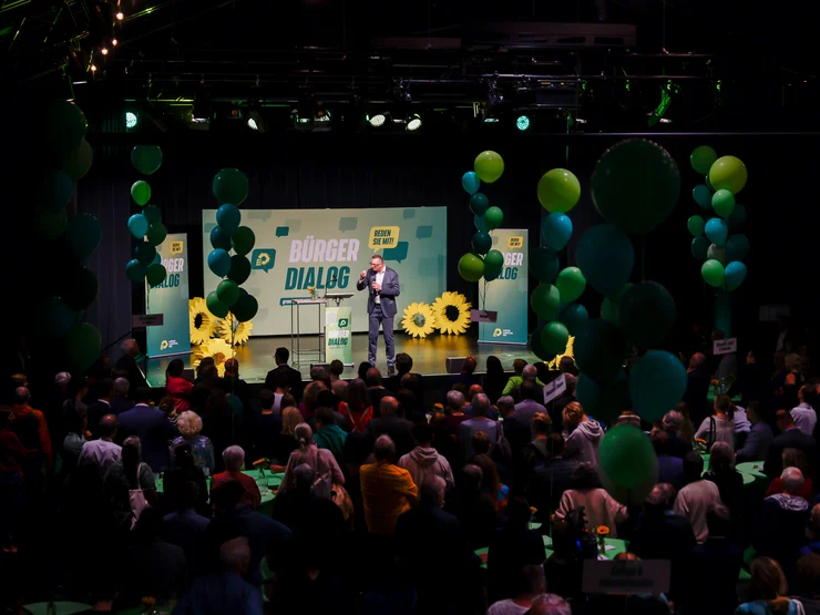 In einem Saal stehen über 400 Menschen und hören dem grünen Fraktionschef auf der Bühne zu