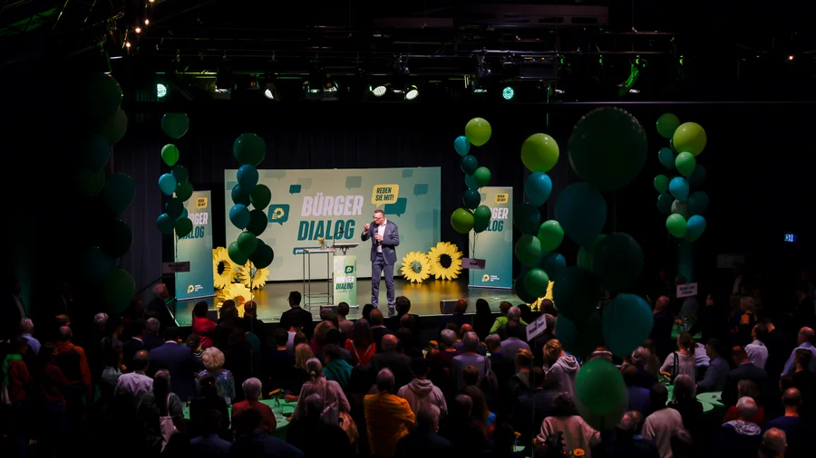 In einem Saal stehen über 400 Menschen und hören dem grünen Fraktionschef auf der Bühne zu
