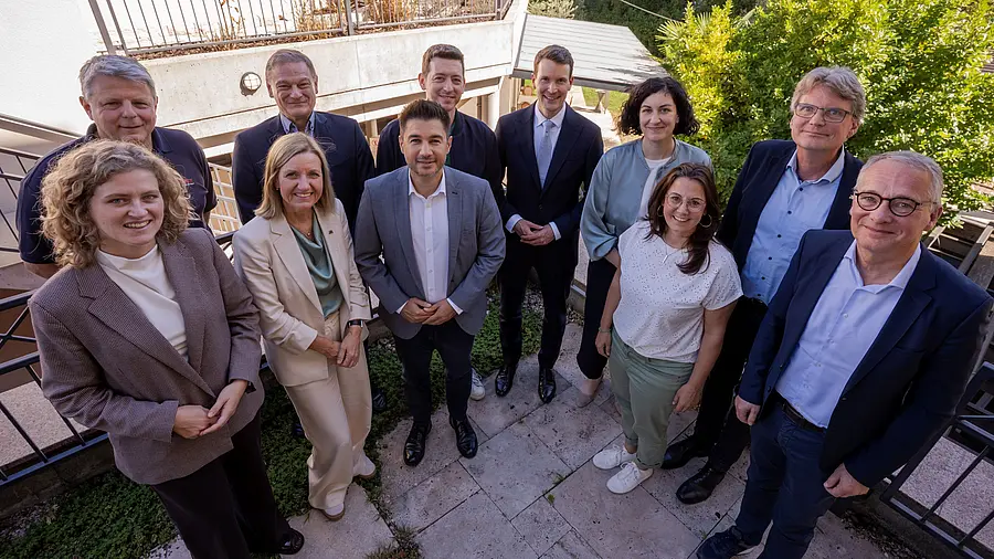 Eine Gruppe von Menschen steht auf einer Terrasse und lächelt in die Kamera
