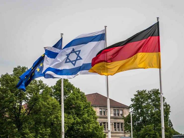 Die EU-, die israelische und die deutsche Fahne wehen im Wind.