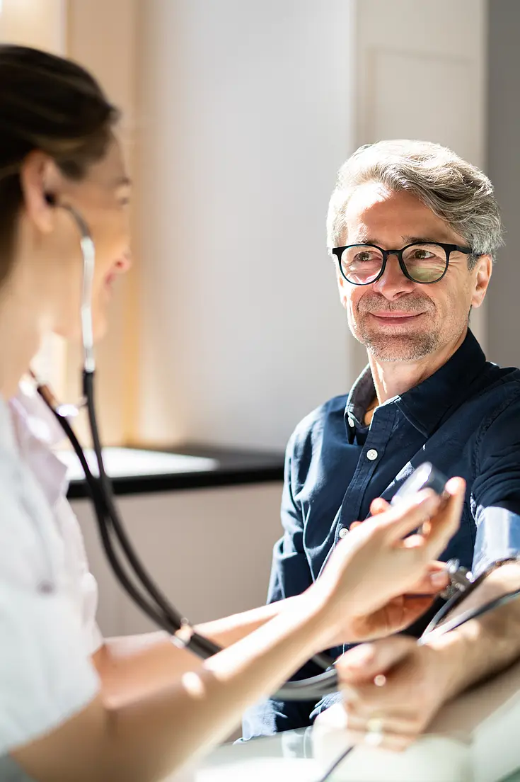 Pflegekraft misst den Puls eines Patienten.