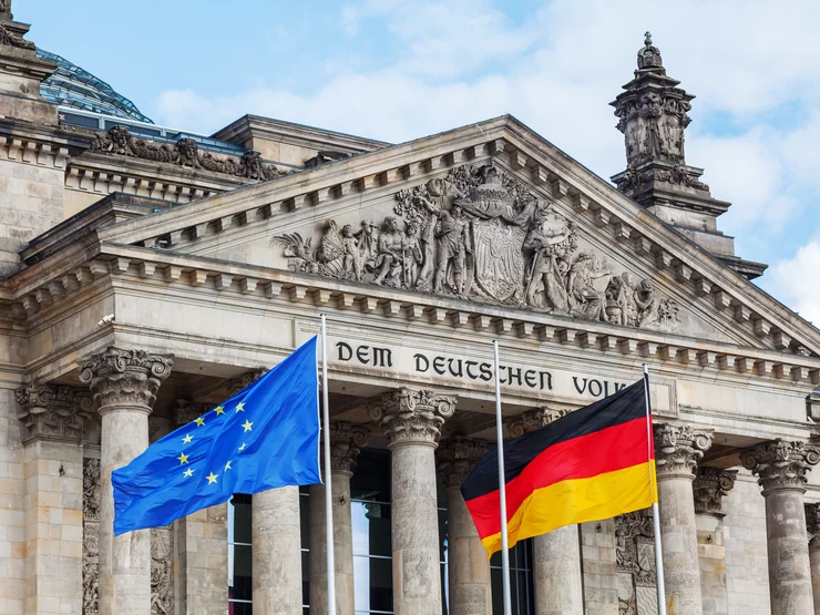Das Bundestagsgebäude, vor dem eine Europa- und eine Deutschlandflagge wehen.