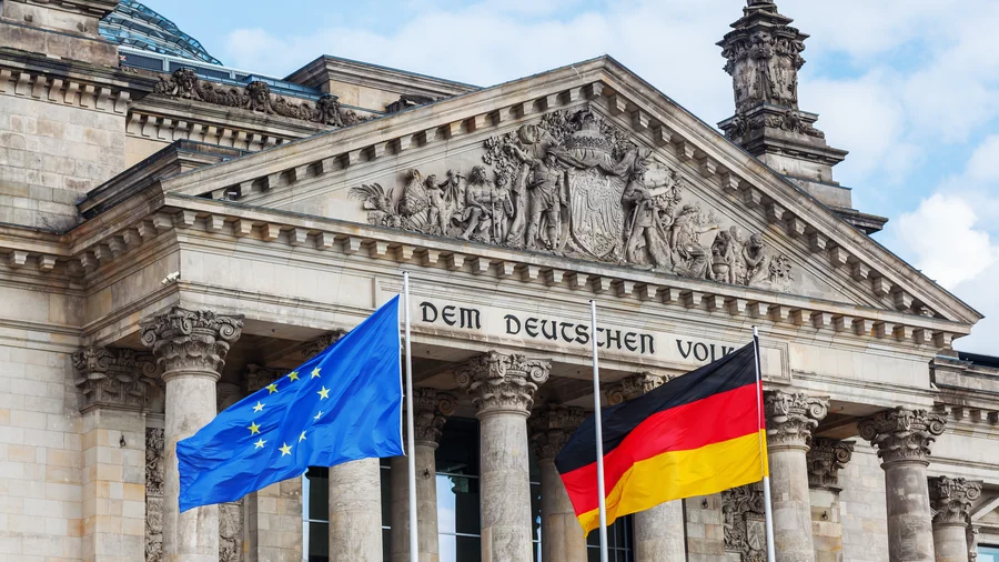Das Bundestagsgebäude, vor dem eine Europa- und eine Deutschlandflagge wehen.