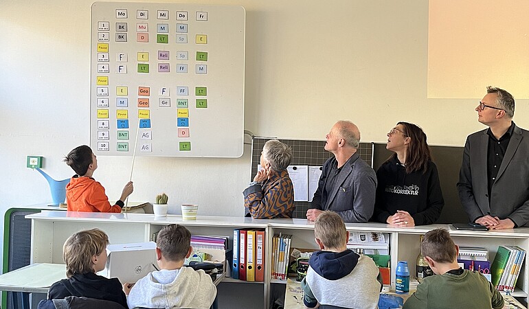 Foto im Klassenzimmer mit Schülerinnen und Abgeordneten vor Tafel