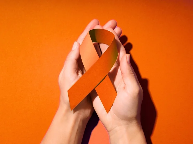 Hände halten eine orangene Schleife.