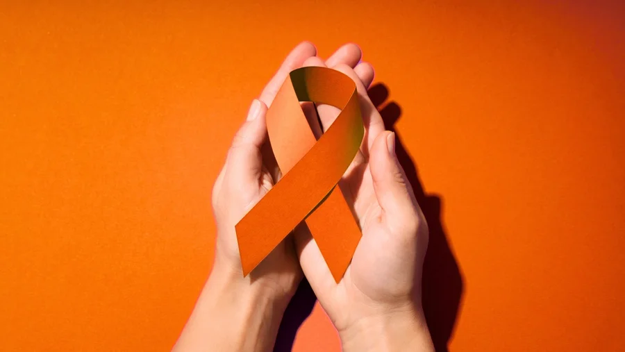 Hände halten eine orangene Schleife.