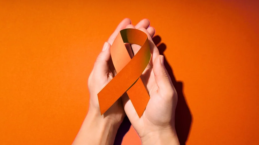 Hände halten eine orangene Schleife.