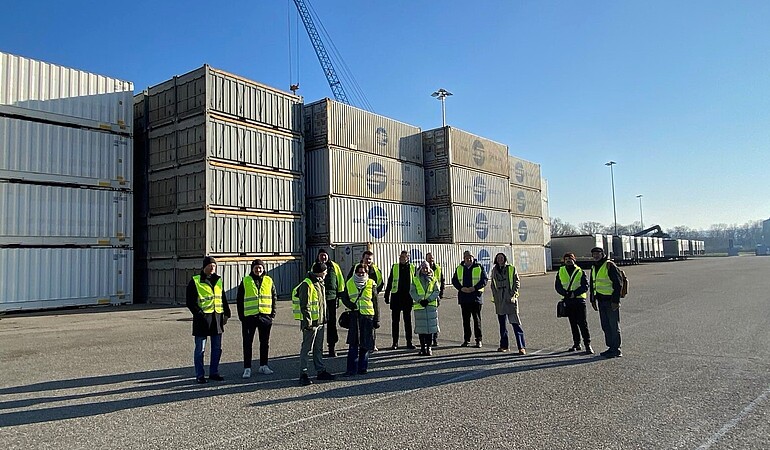 Gruppenbild der Beteiligten am Hafen, im Hintergrund Container