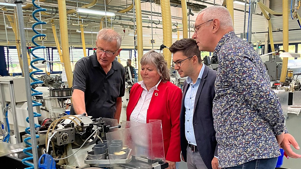 Vier Menschen stehen interessiert vor einer Maschine