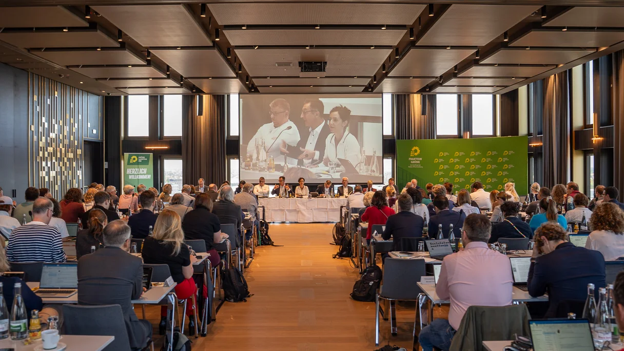 In einem Saal sitzt die Grüne Fraktion von Baden-Württemberg