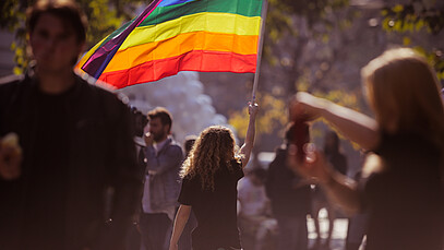 Frau hält eine Pride Flagge in die Höhe