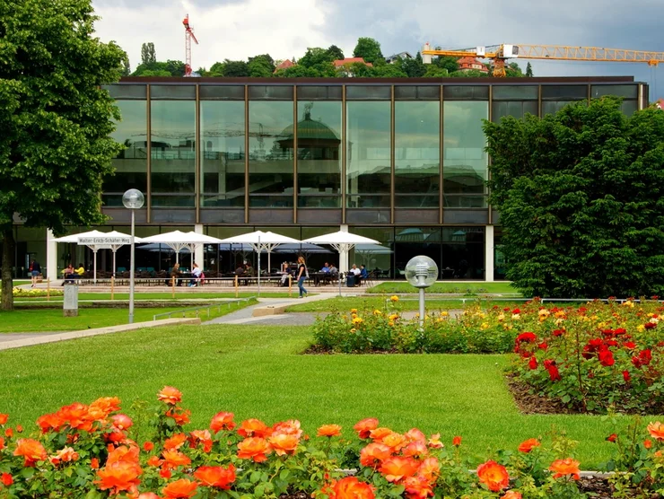Der Landtag von Baden-Württemberg umgeben von Blumen und grünen Bäumen.