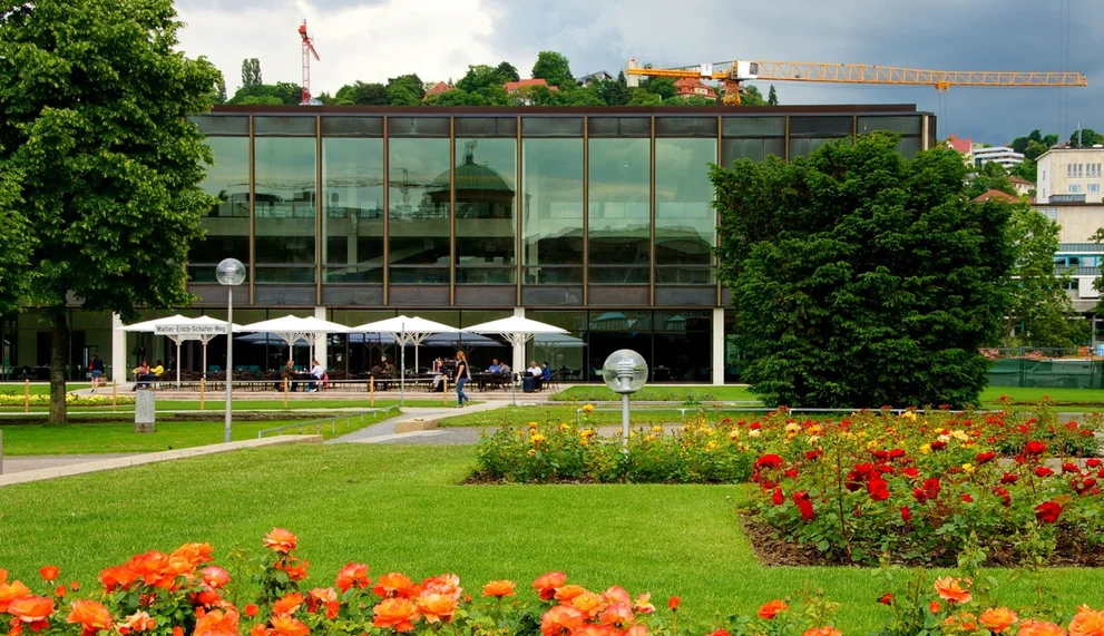 Der Landtag von Baden-Württemberg umgeben von Blumen und grünen Bäumen.