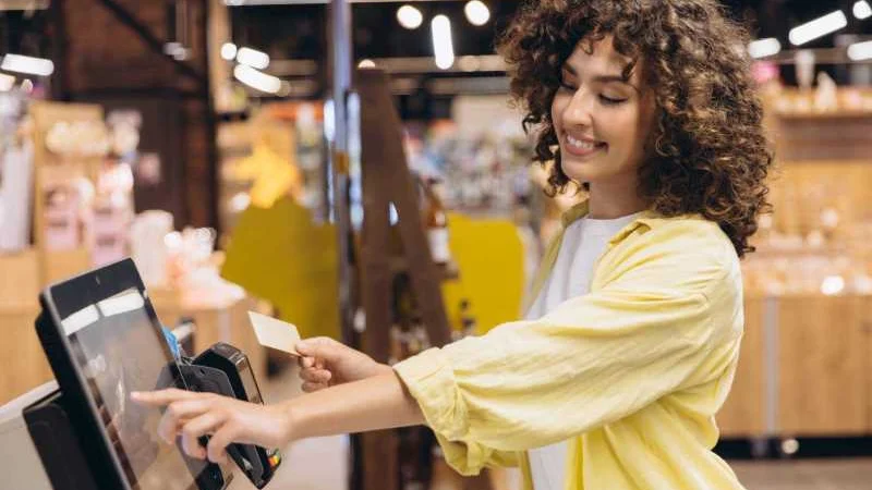 Junger Mensch lächelt beim Bezahlen eines Einkaufs an einer Self-Service-Kasse
