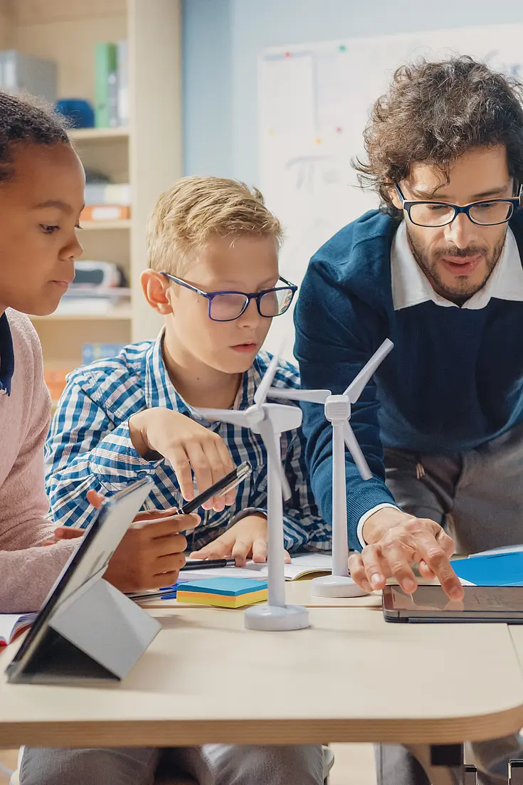 Lehrer zeigt seinen Schüler:innen ein kleines Windkraftmodell