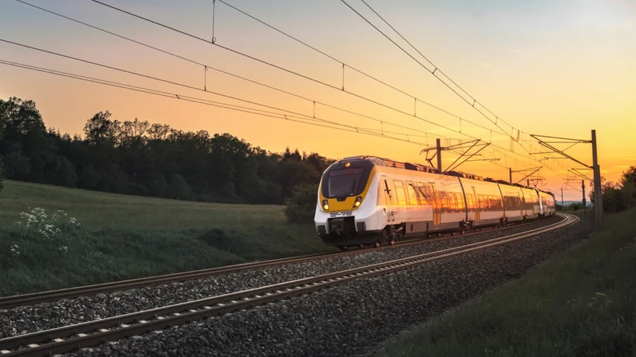 Eine Bahn auf der Schiene, im Hintergrund ein Abendhimmel.
