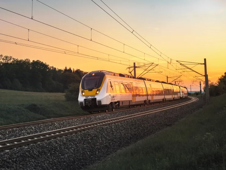 Eine Bahn auf der Schiene, im Hintergrund ein Abendhimmel.