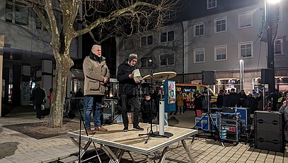 Zwei Männer stehen auf einer Bühne und halten eine Rede.