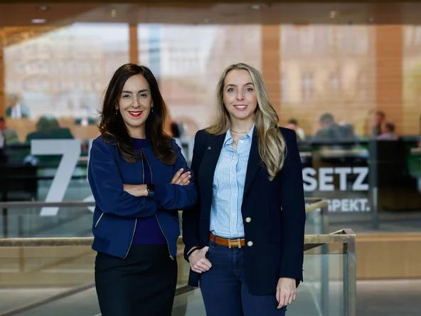 Zwei Abgeordnete stehen vor dem Plenarsaal.