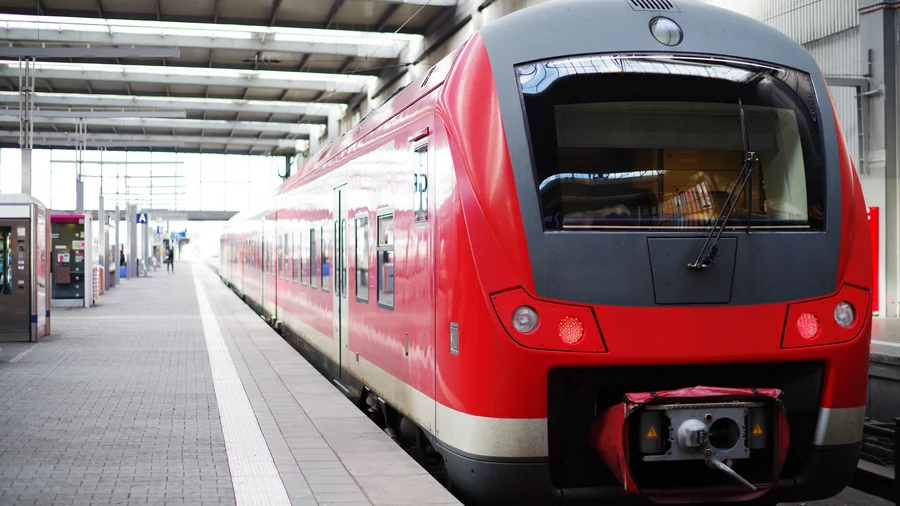 Roter Regionalzug steht an einem leeren Gleis im Bahnhof