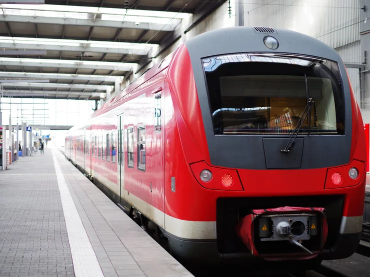 Roter Regionalzug steht an einem leeren Gleis im Bahnhof