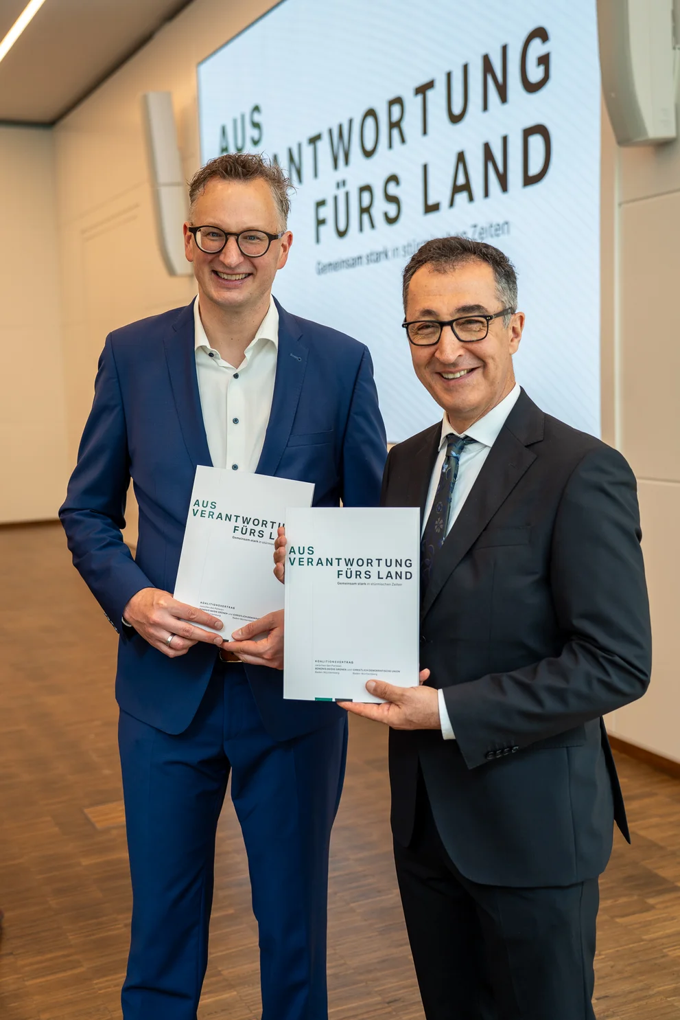 Andreas Schwarz und Cem Özdemir halten den Koalitionsvertrag in ihren Händen 