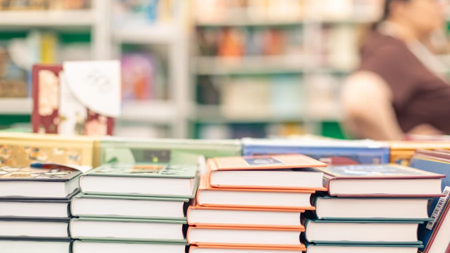 Bücherstapel, im Hintergrund Regale