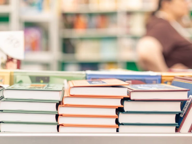 Bücherstapel, im Hintergrund Regale