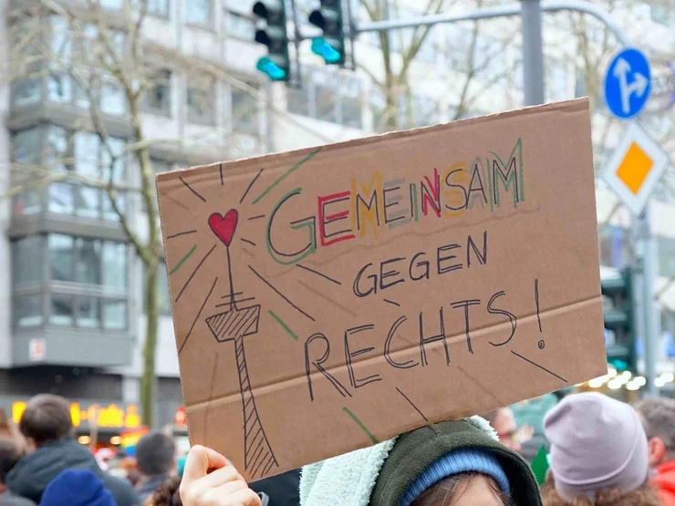 Jemand hält auf einer Demo ein Schild "Gemeinsam gegen rechts" hoch.