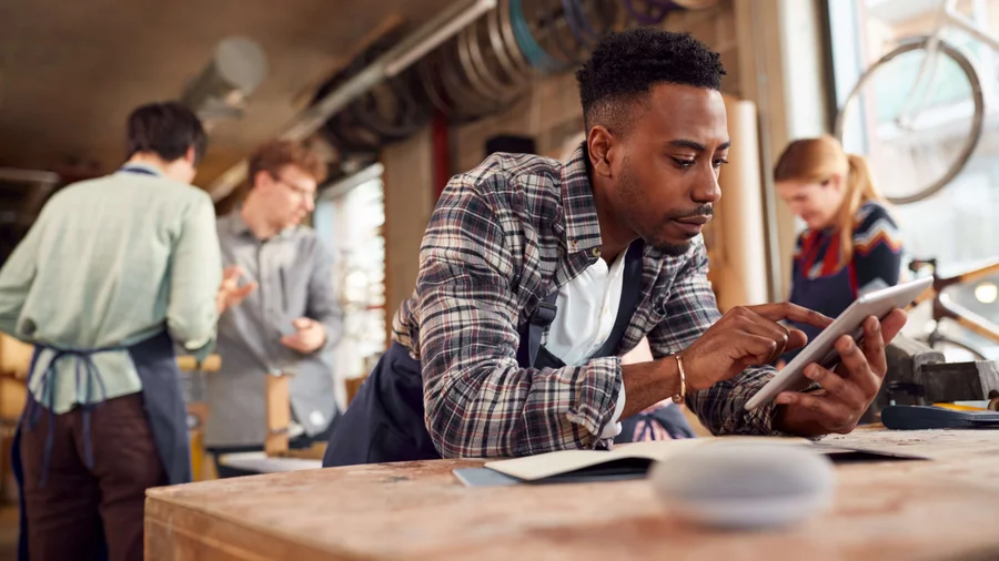 Mann guckt konzentriert auf sein Tablet in einem StartUp-Farradladen, das Bambus-Räder entwickelt.