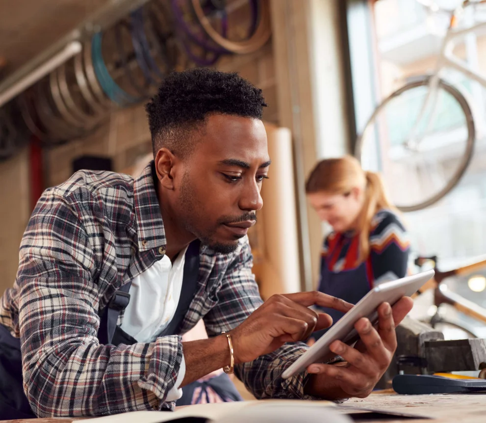 Mann guckt konzentriert auf sein Tablet in einem StartUp-Farradladen, das Bambus-Räder entwickelt.